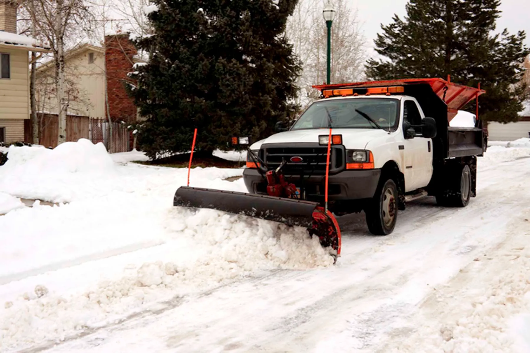 Snow removal crew clearing parking lot with plow truck